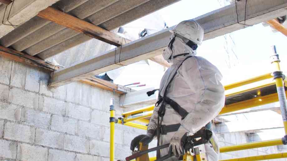 Man in PPE inspecting a building.