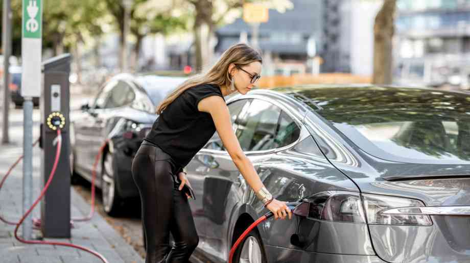 Woman charging car at kerbside Woman charging car at kerbside