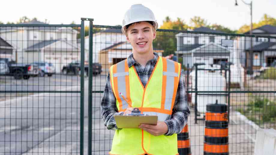 Young apprentice in hi-vis jacket with clipboard