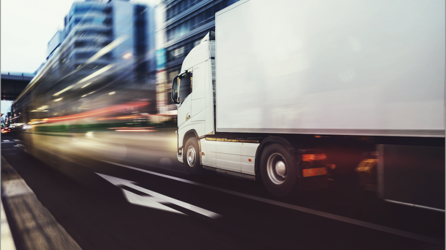 Lorry on a road with blurred vehicle lights ahead.